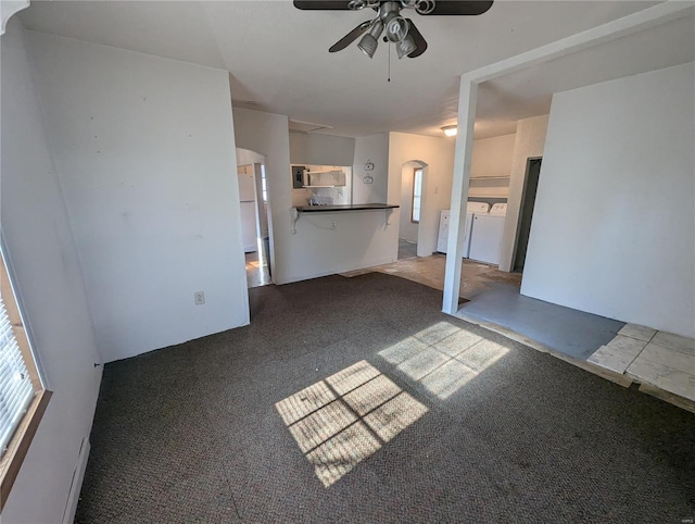 unfurnished living room with washer and dryer, dark colored carpet, and ceiling fan