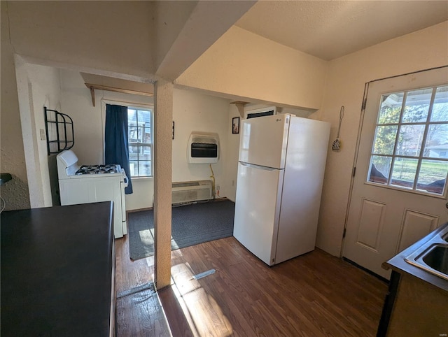 kitchen featuring heating unit, dark wood-type flooring, and white appliances