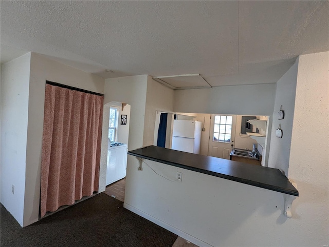 kitchen with washer / dryer, dark carpet, a textured ceiling, and white refrigerator