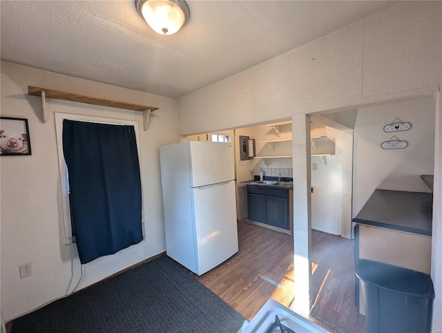 kitchen with a textured ceiling, white refrigerator, dark hardwood / wood-style floors, and sink