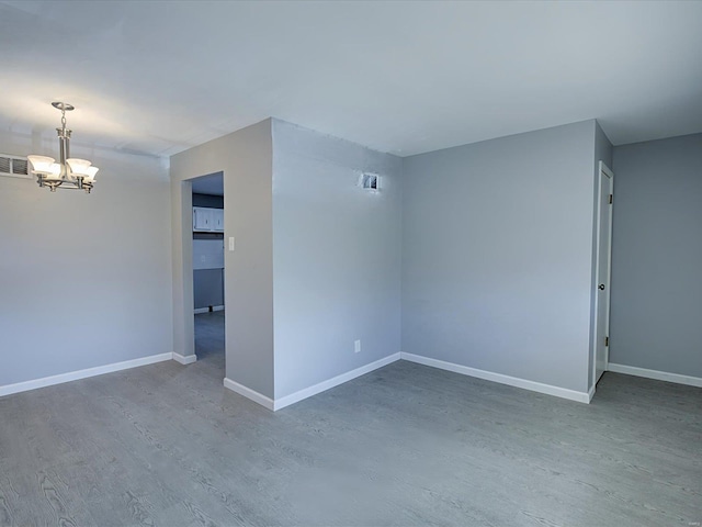 spare room featuring a notable chandelier and hardwood / wood-style flooring