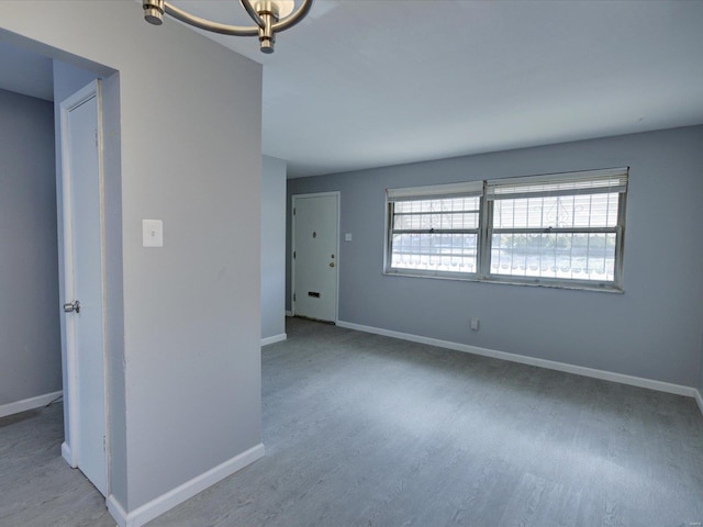 spare room with an inviting chandelier and light hardwood / wood-style flooring