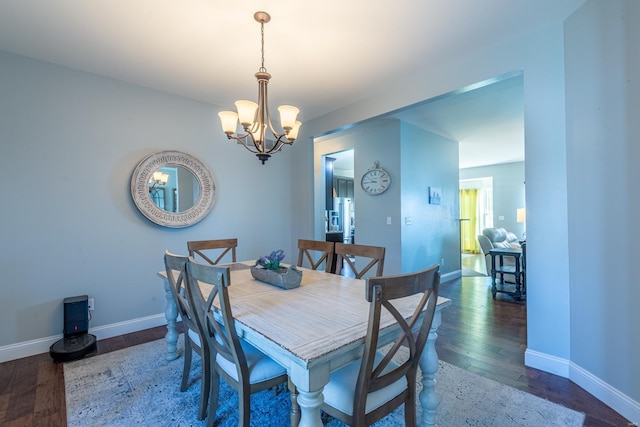 dining area with a notable chandelier and dark hardwood / wood-style flooring