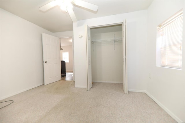 unfurnished bedroom featuring ceiling fan, light carpet, and a closet