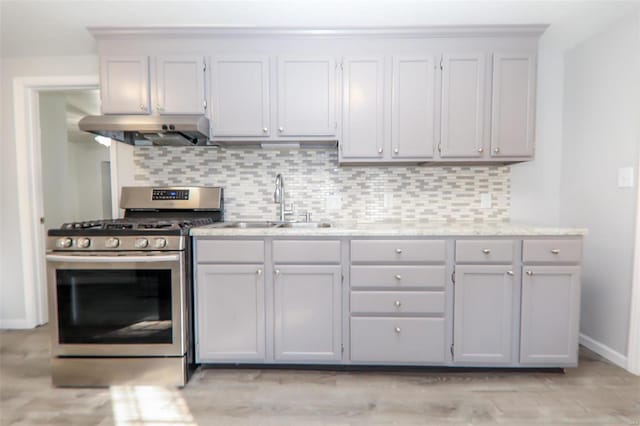 kitchen featuring sink, tasteful backsplash, stainless steel gas range oven, and exhaust hood