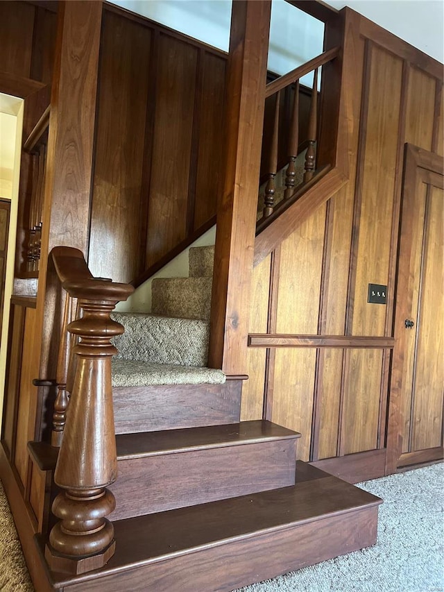 stairway with carpet floors and wooden walls