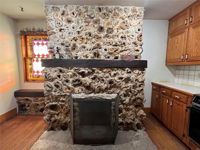 details featuring backsplash, electric range, tile counters, and hardwood / wood-style flooring