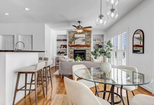 dining room with light hardwood / wood-style floors, ceiling fan, a fireplace, built in features, and sink