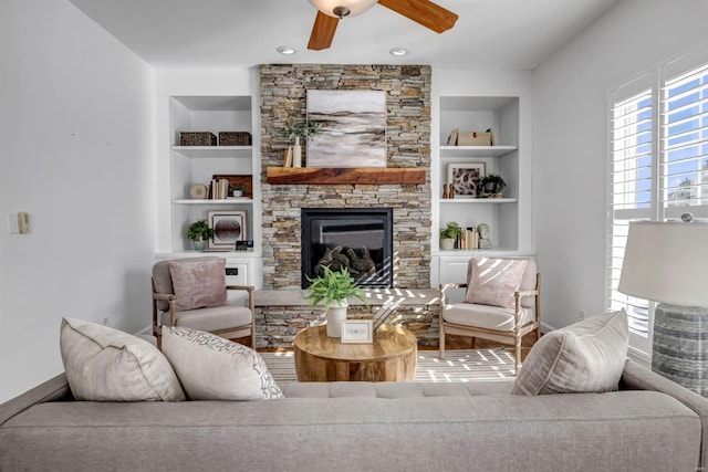 living room featuring ceiling fan, a fireplace, and built in shelves