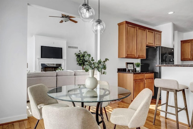 dining room featuring ceiling fan, a high end fireplace, and light hardwood / wood-style flooring