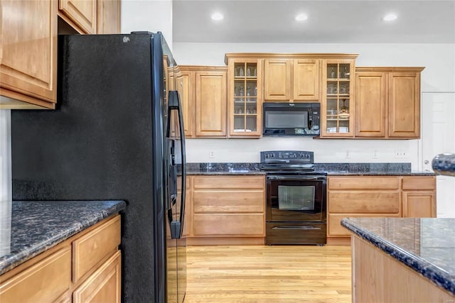 kitchen featuring black appliances, dark stone counters, and light hardwood / wood-style flooring