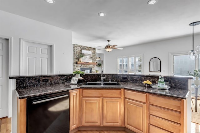 kitchen with ceiling fan, dishwasher, sink, hanging light fixtures, and dark stone counters