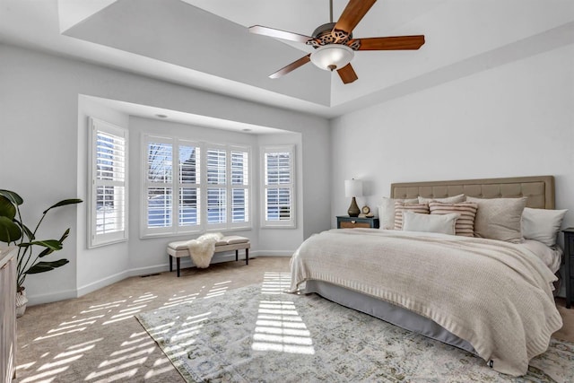 bedroom with ceiling fan, carpet flooring, and a raised ceiling