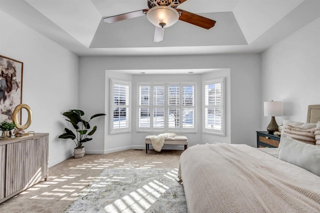 bedroom with light carpet, ceiling fan, and a raised ceiling