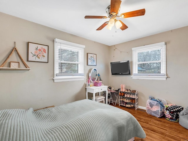 bedroom with multiple windows, ceiling fan, and wood-type flooring