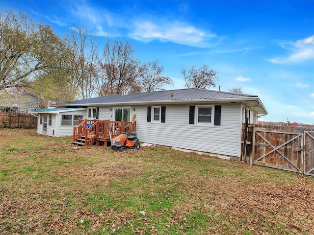 back of property with a deck and a lawn