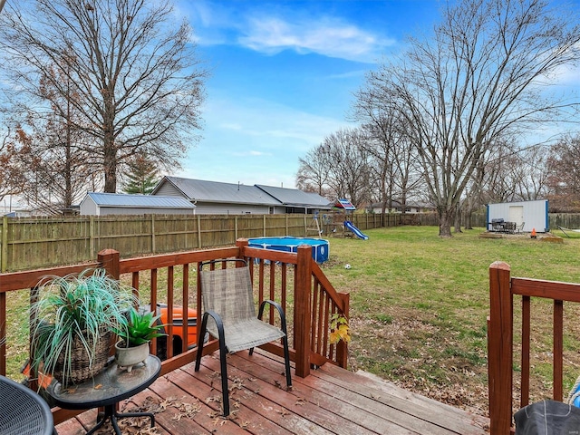 wooden terrace featuring a lawn and a playground