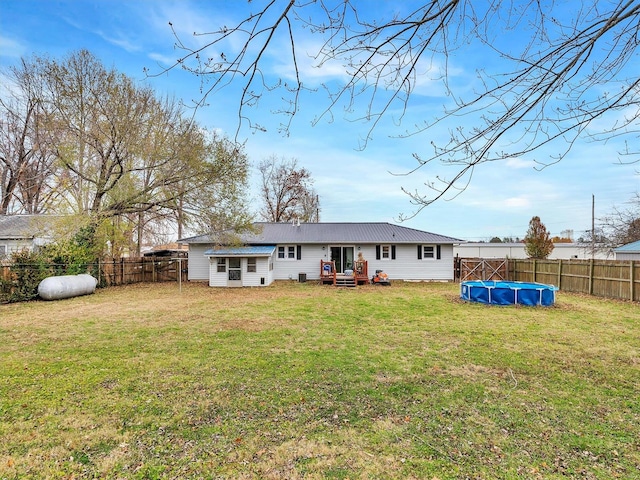 rear view of house featuring a fenced in pool and a lawn