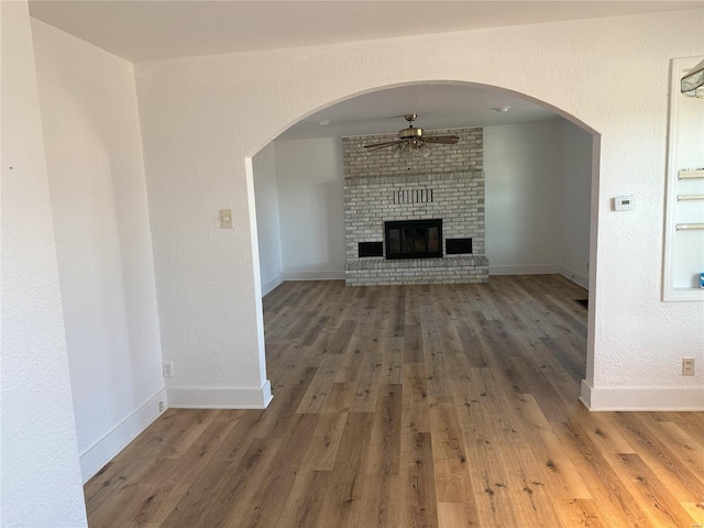 unfurnished living room with a fireplace, dark hardwood / wood-style flooring, and ceiling fan