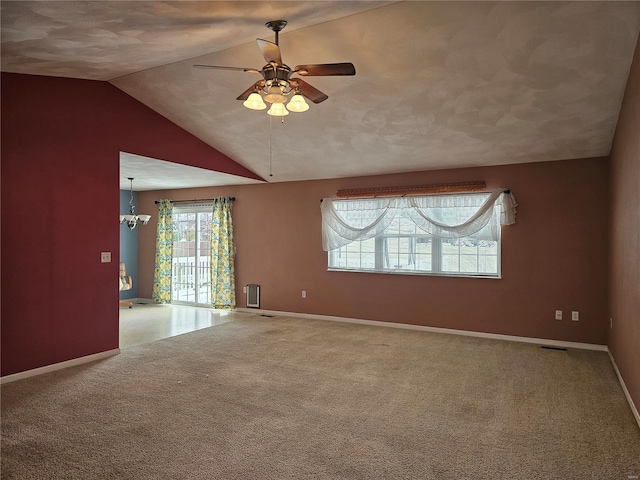 spare room with ceiling fan with notable chandelier, carpet floors, and vaulted ceiling