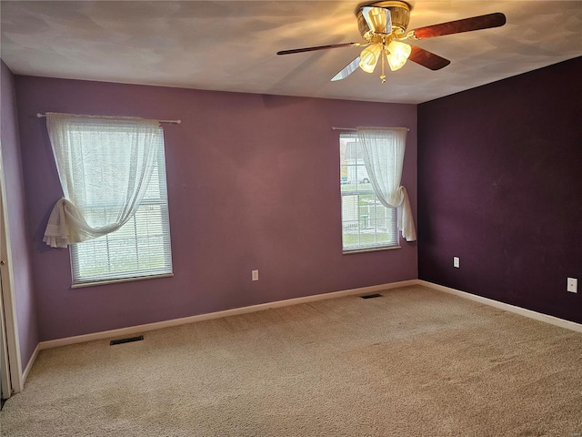 carpeted empty room with a wealth of natural light and ceiling fan