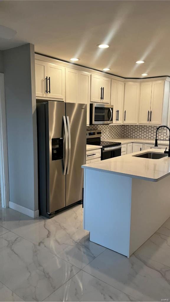 kitchen with stainless steel appliances, white cabinetry, tasteful backsplash, and sink