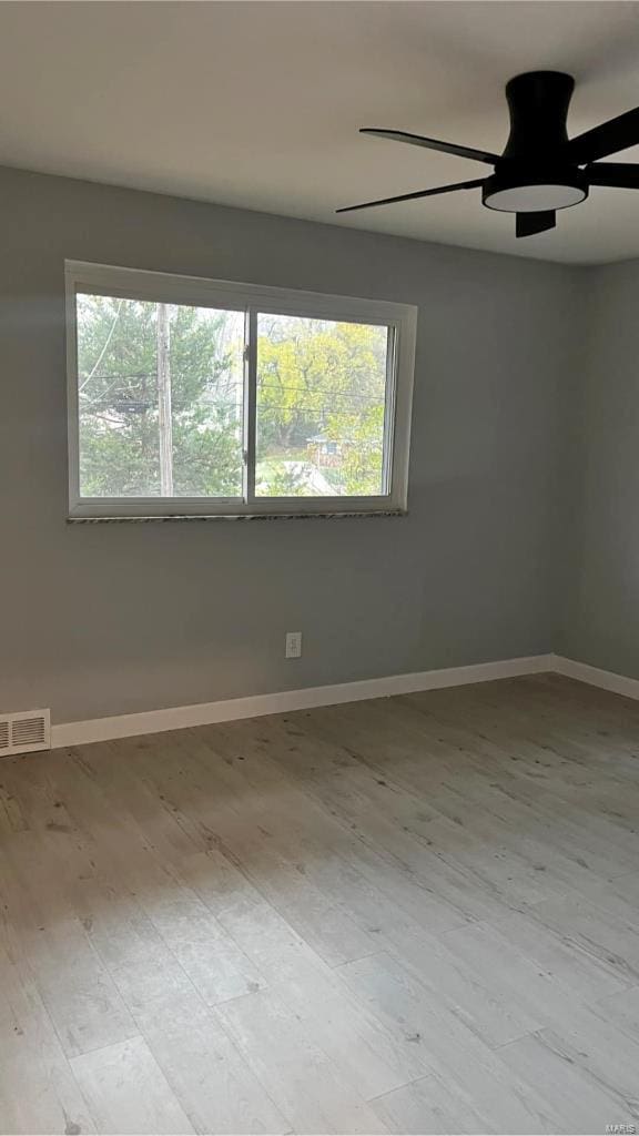 empty room with ceiling fan, a healthy amount of sunlight, and light hardwood / wood-style floors