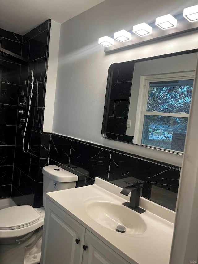 bathroom with vanity, backsplash, toilet, tiled shower, and tile walls