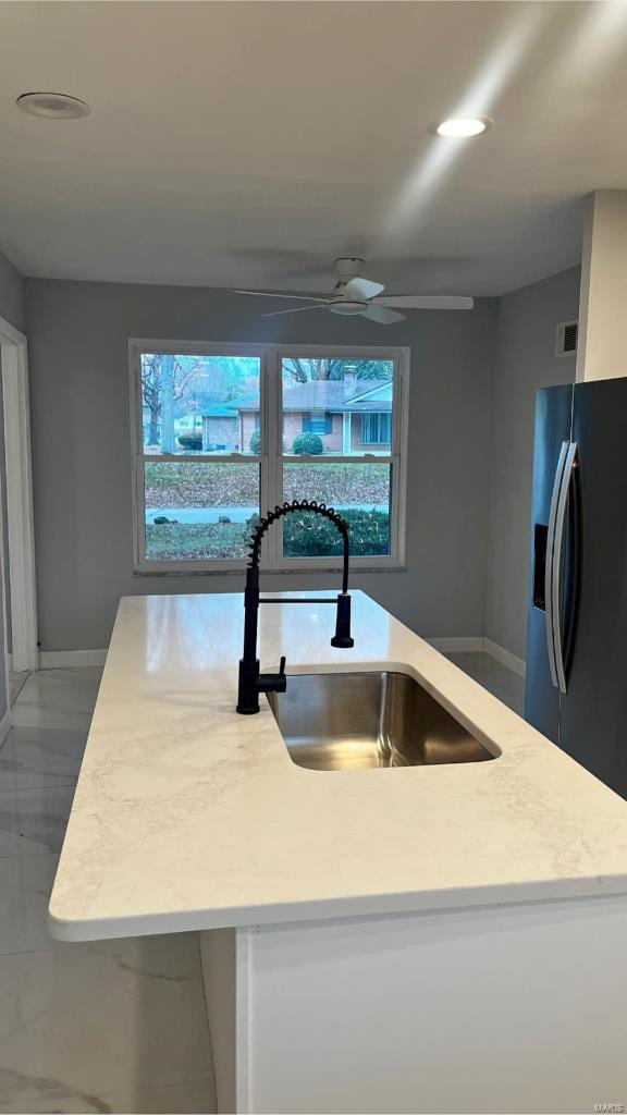 kitchen featuring stainless steel refrigerator with ice dispenser, an island with sink, plenty of natural light, and sink