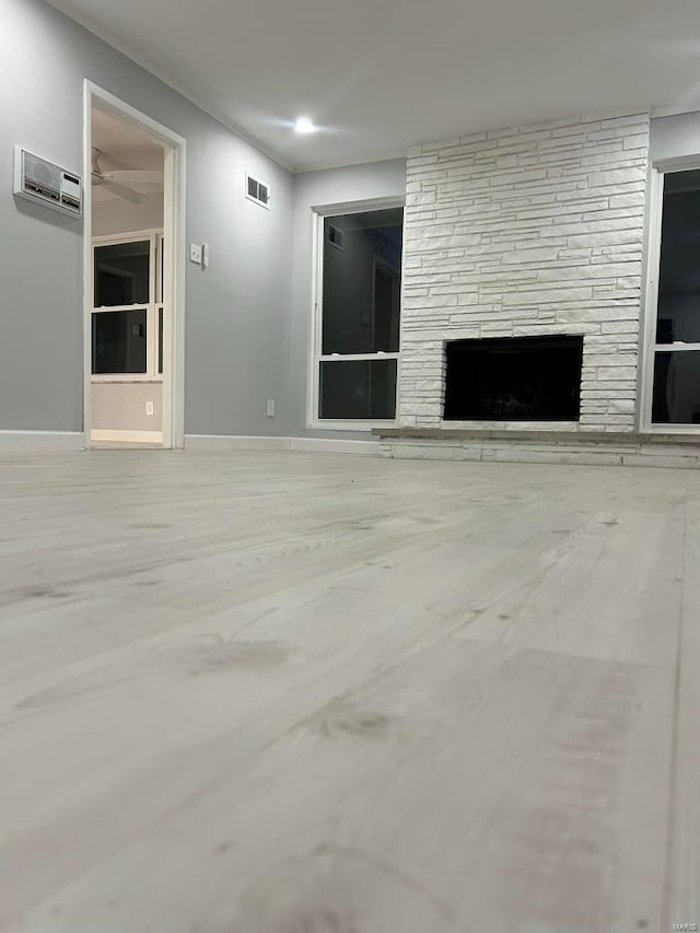 unfurnished living room with a stone fireplace and an AC wall unit