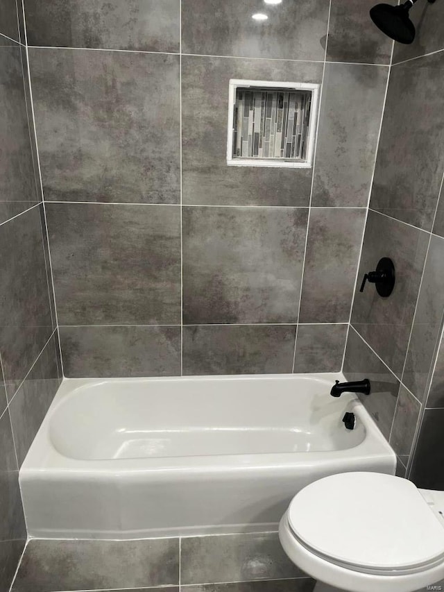 bathroom featuring toilet and tiled shower / bath