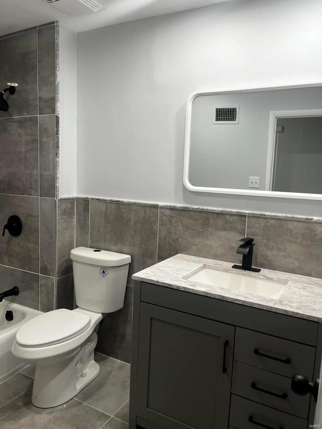 full bathroom featuring tile patterned floors, vanity, tile walls, toilet, and tiled shower / bath