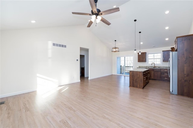 interior space with sink, a center island, stainless steel fridge, pendant lighting, and light wood-type flooring