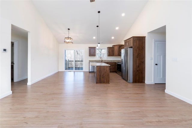 kitchen with stainless steel appliances, high vaulted ceiling, pendant lighting, light hardwood / wood-style floors, and a kitchen island