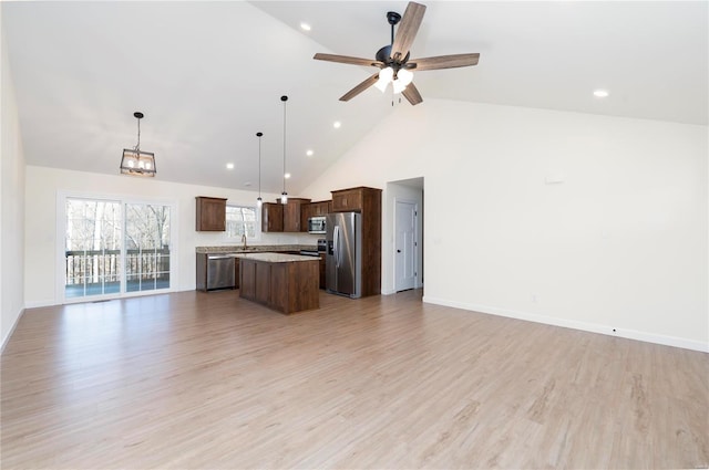 kitchen featuring a kitchen island, hanging light fixtures, light wood-type flooring, and appliances with stainless steel finishes