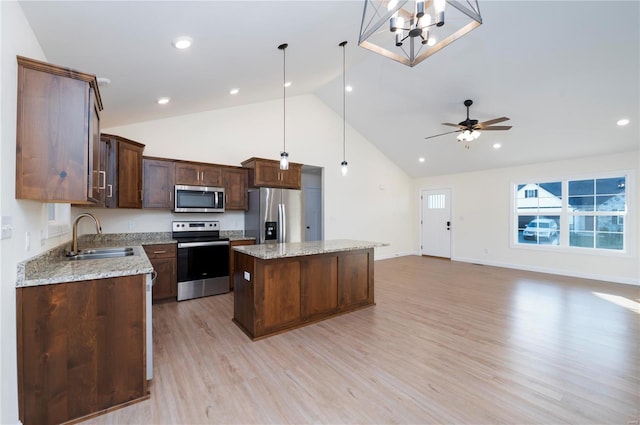 kitchen with stainless steel appliances, sink, pendant lighting, light hardwood / wood-style flooring, and a kitchen island