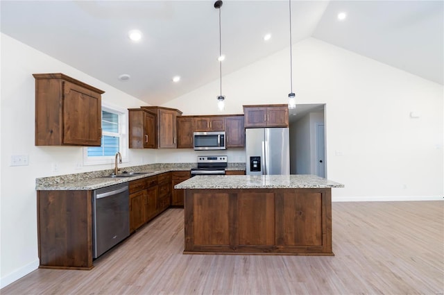 kitchen with hanging light fixtures, stainless steel appliances, light wood-type flooring, and sink