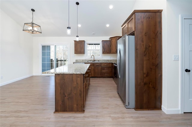 kitchen featuring a center island, sink, hanging light fixtures, light hardwood / wood-style flooring, and stainless steel fridge