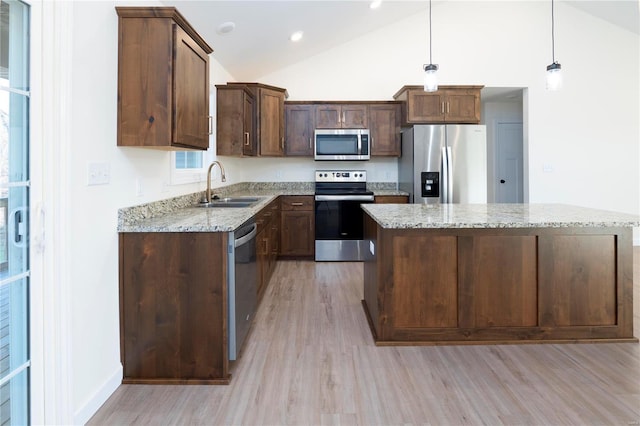 kitchen featuring a center island, sink, light wood-type flooring, decorative light fixtures, and stainless steel appliances