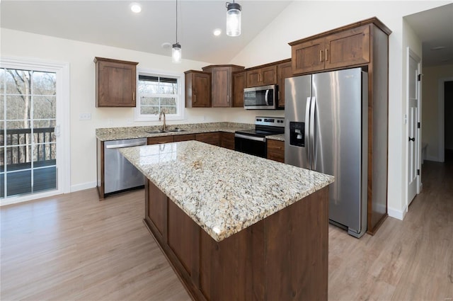 kitchen with pendant lighting, a center island, lofted ceiling, light hardwood / wood-style flooring, and appliances with stainless steel finishes