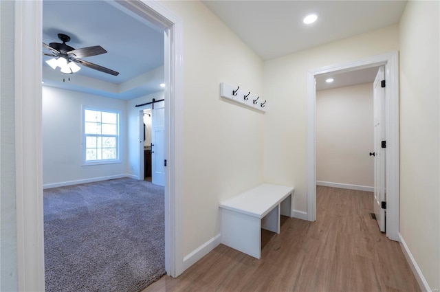 corridor with a barn door and light hardwood / wood-style flooring