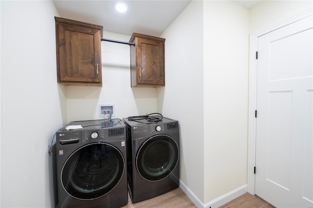 clothes washing area with cabinets, light hardwood / wood-style flooring, and washing machine and clothes dryer