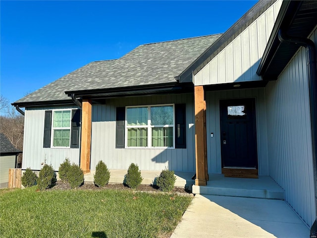 doorway to property featuring covered porch and a lawn