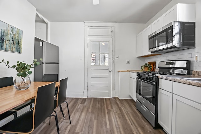 kitchen featuring tasteful backsplash, white cabinetry, dark hardwood / wood-style flooring, and stainless steel appliances