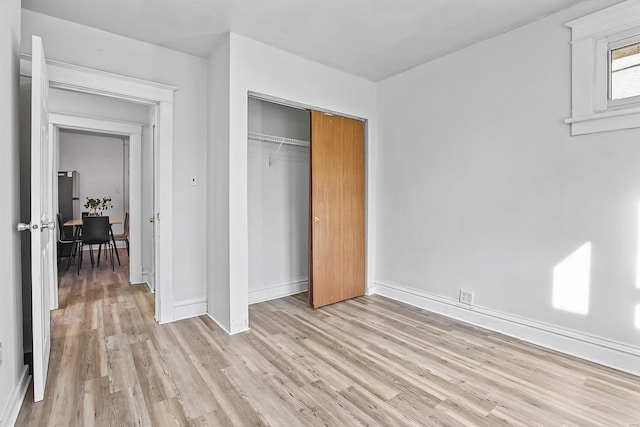 unfurnished bedroom with a closet and light hardwood / wood-style flooring