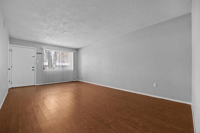 unfurnished room with dark hardwood / wood-style flooring and a textured ceiling