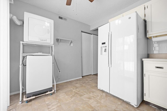 laundry room featuring a textured ceiling, ceiling fan, and stacked washer / drying machine