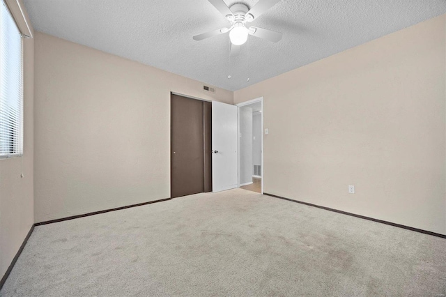 unfurnished bedroom with a textured ceiling, light colored carpet, and ceiling fan