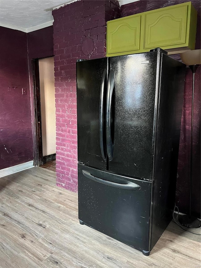 room details with green cabinetry, black fridge, and light hardwood / wood-style flooring