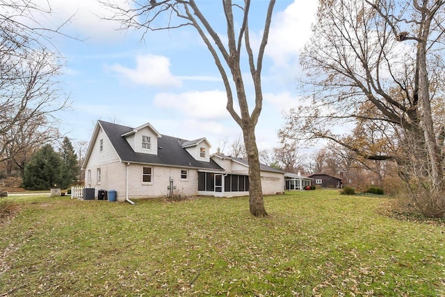 back of house featuring a sunroom, cooling unit, and a lawn